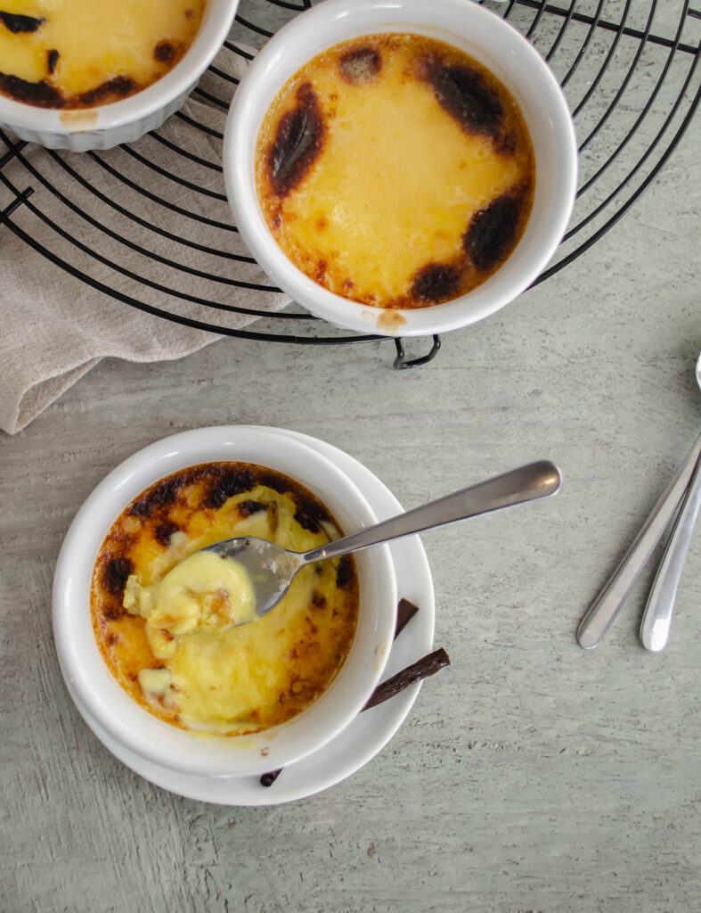 creme brulee in a ramekin with the top shattered with a spoon