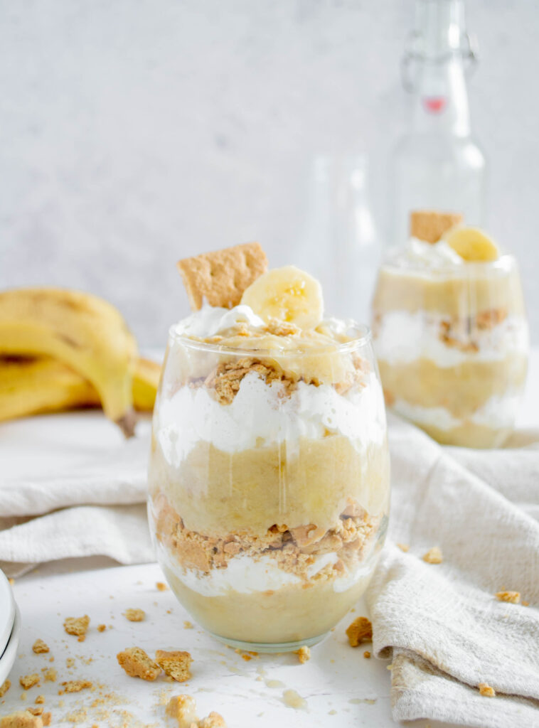 glass full of banana pudding, whipped cream, and crushed graham crackers
