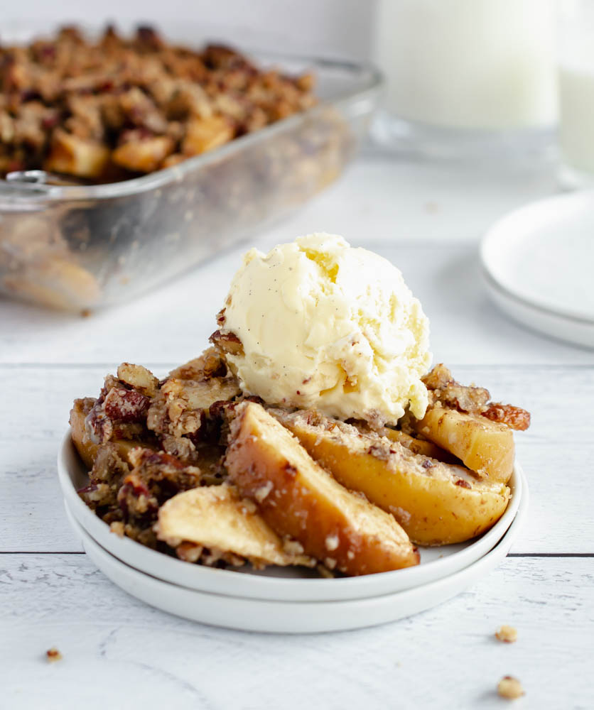 sugar free apple crisp on a white plate topped with vanilla ice cream