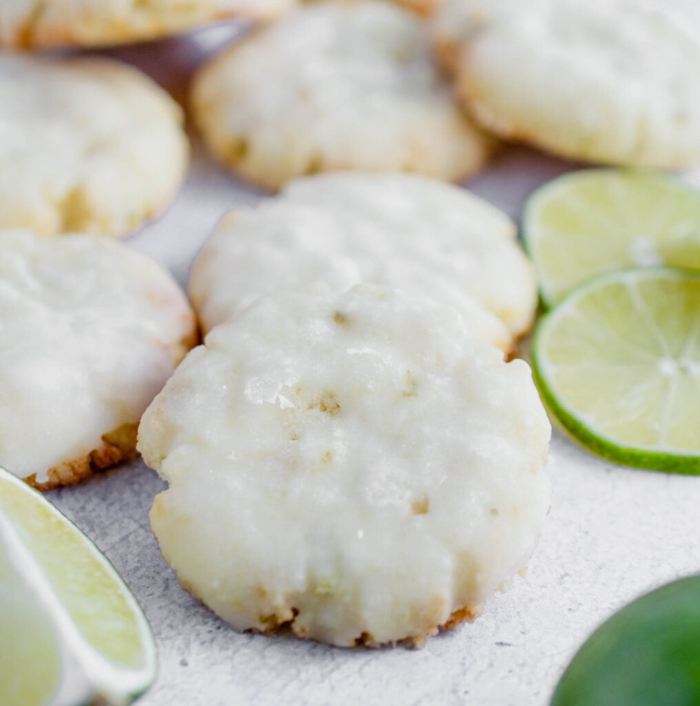 close up photo of a healthy lime cookie surrounded by sliced limes