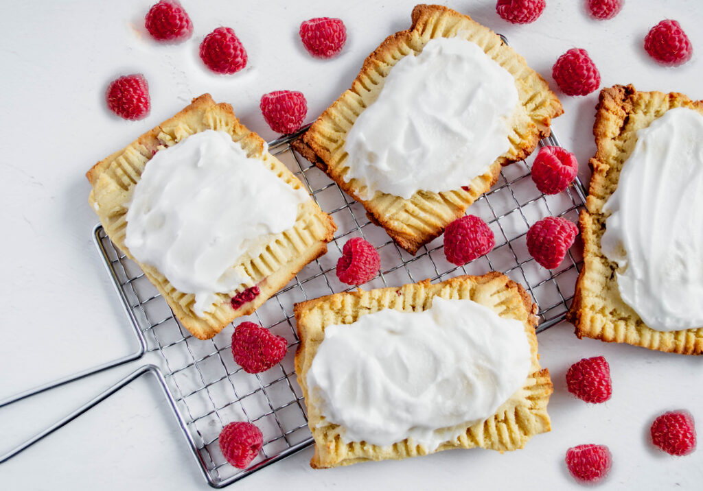 homemade poptarts on a small cooling rack surrounded by raspberries