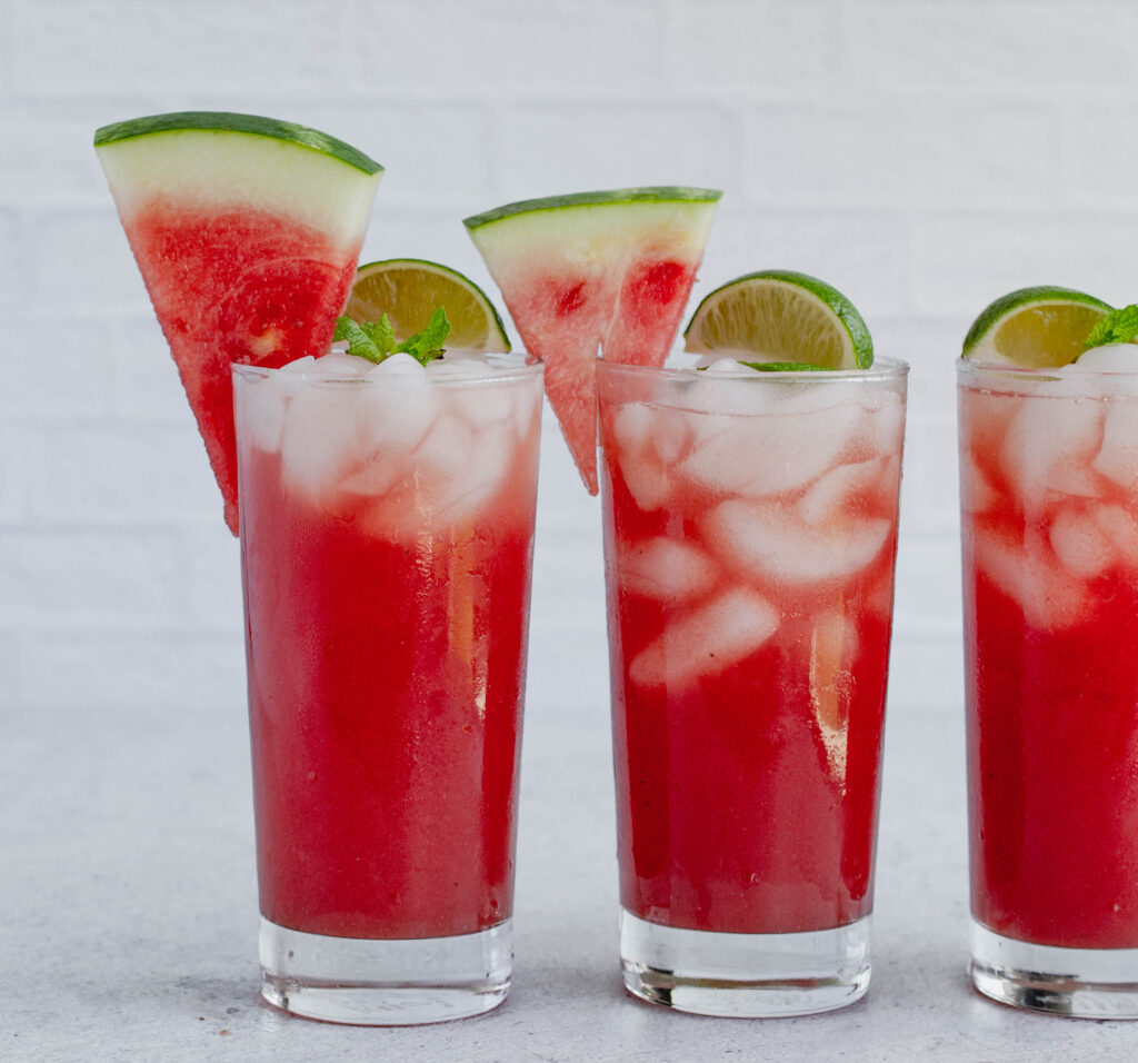 3 glasses of watermelon punch topped with sliced watermelon and sliced lime