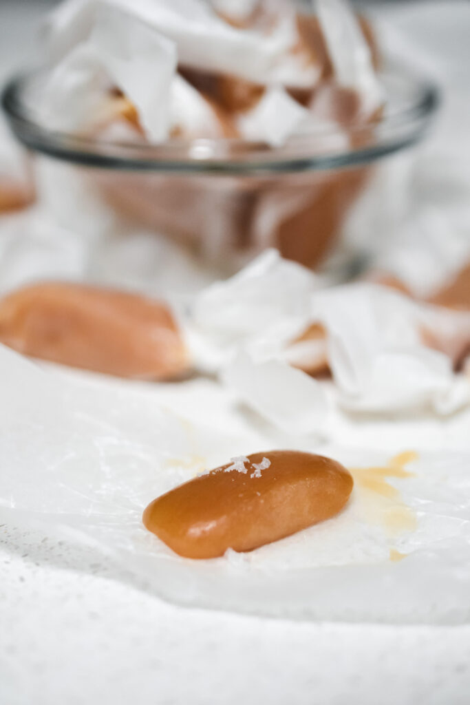close up photo of a soft caramel candy topped with flaked sea salt