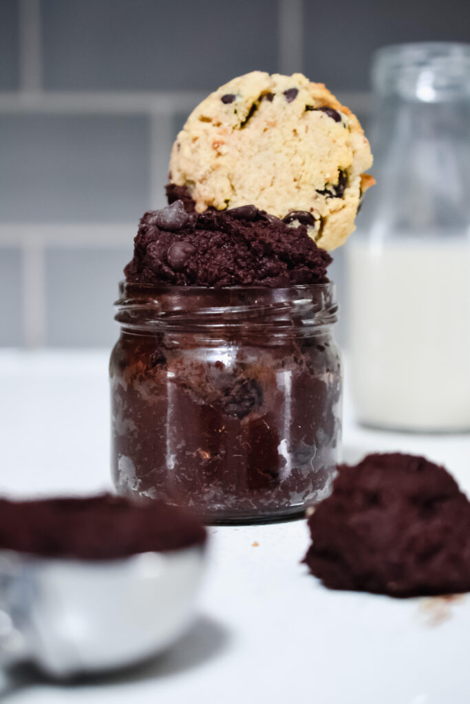 edible brownie batter in a small glass jar topped with a chocolate chip cookie