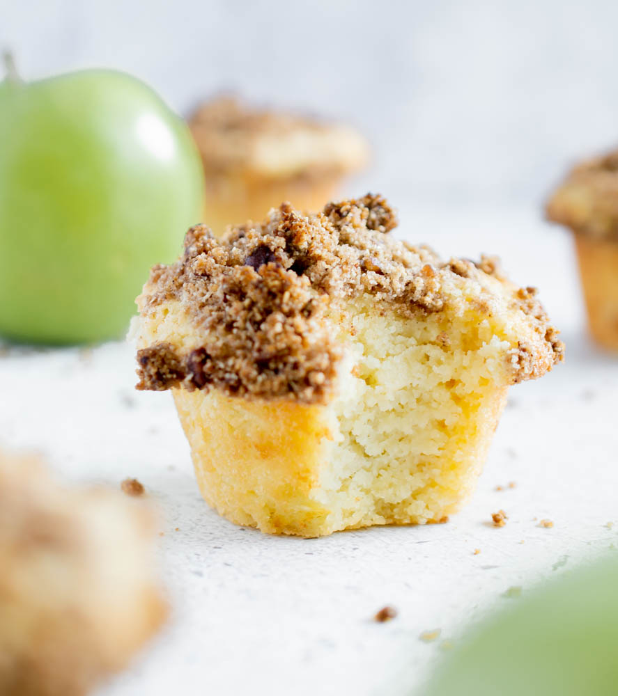 close up photo of gluten free apple crumble muffin with a bite taken out of it