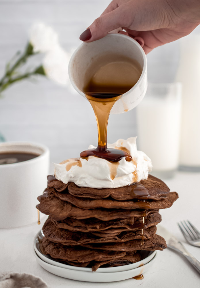 stack of Chocolate Protein Pancakes being drizzled with sugar free syrup
