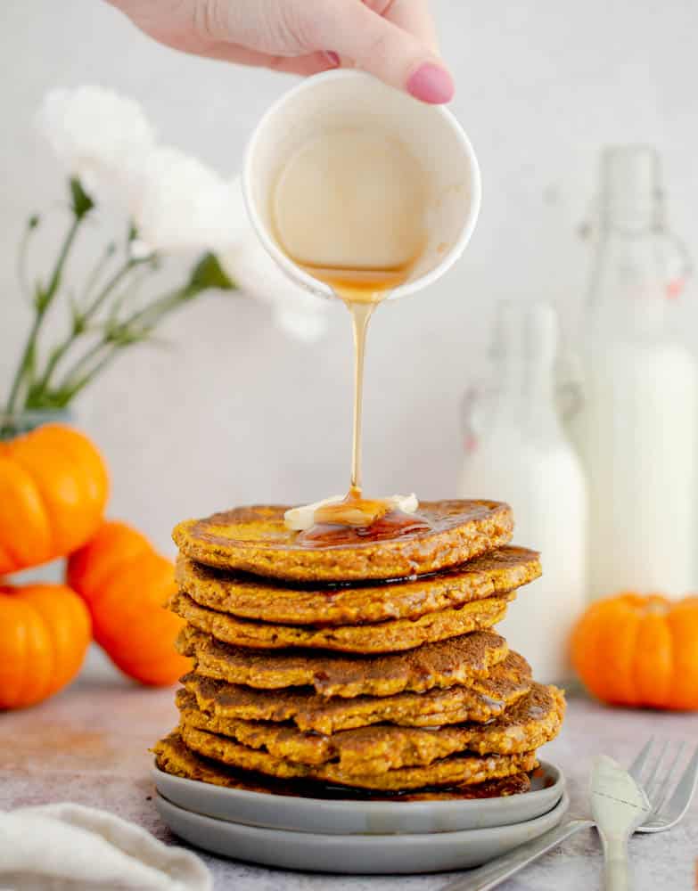 stack of Gluten Free Keto Pumpkin Pancakes being drizzled with maple syrup