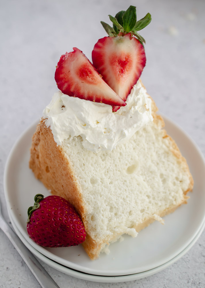 slice of Keto Angel Food Cake topped with whipped cream and strawberries