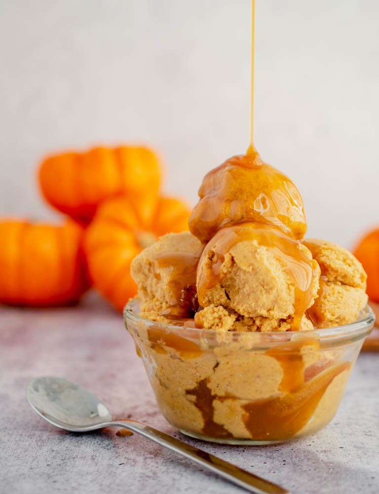 Keto Dairy Free Pumpkin Ice Cream drizzled in caramel sauce in a clear bowl.