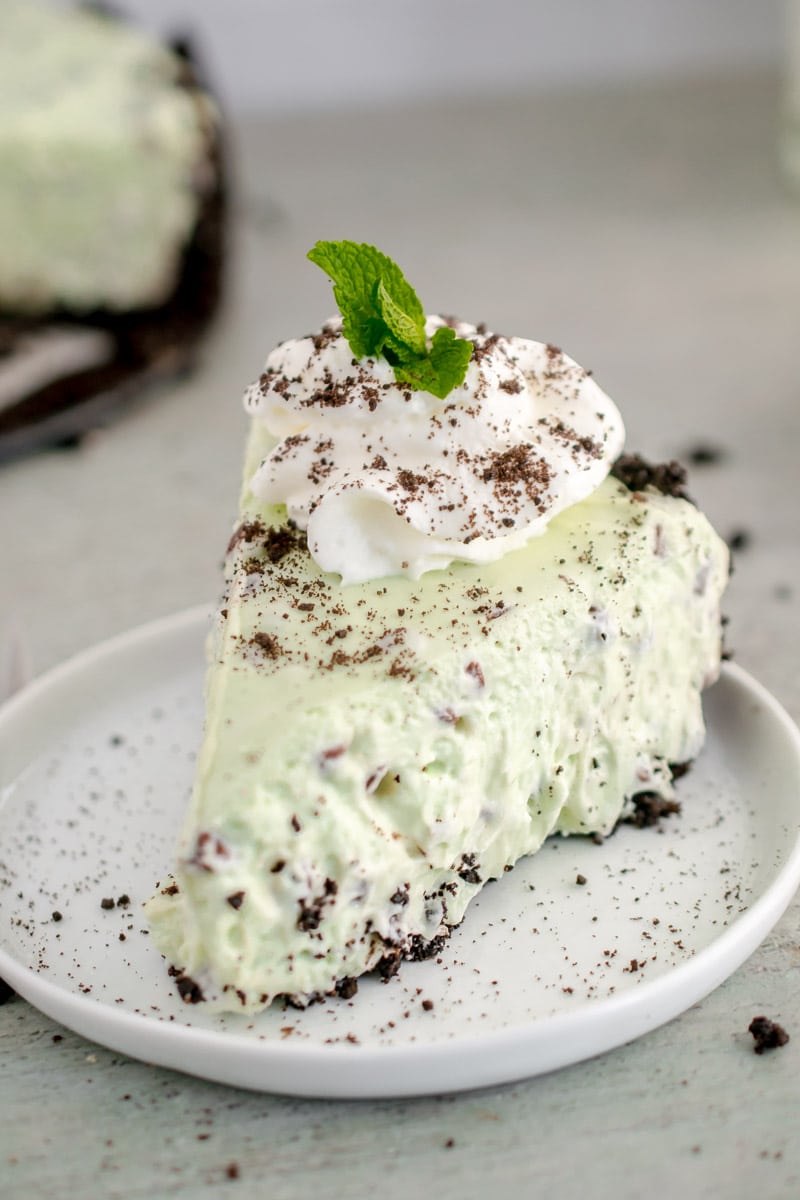 slice of Mint Chocolate Cheesecake topped with whipped cream and a mint leaf