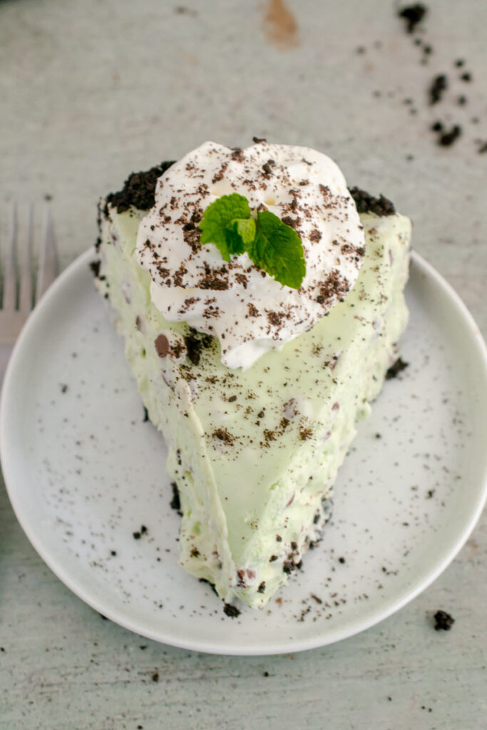 slice of Mint Chocolate Cheesecake topped with whipped cream and a mint leaf