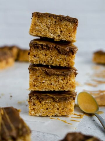 stack of 4 Chocolate Peanut Butter Rice Krispies with a peanut butter covered spoon