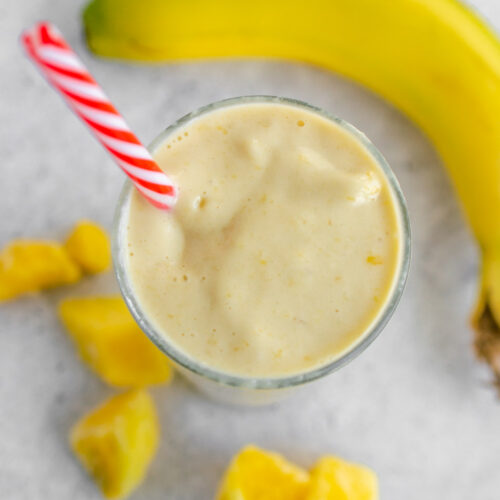 overhead photo of banana peach smoothie in a glass