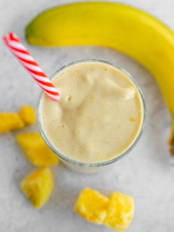overhead photo of banana peach smoothie in a glass