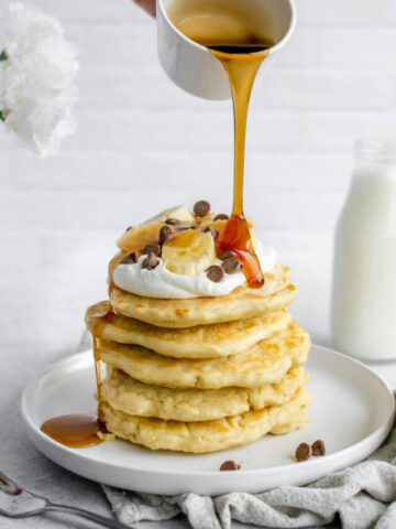 stack of dairy free pancakes topped with bananas and dairy free whipped cream