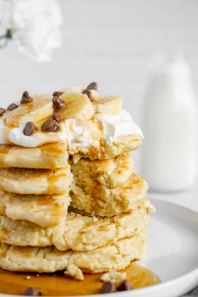 stack of dairy free pancakes topped with bananas and dairy free whipped cream