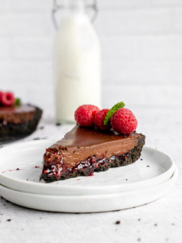 Slice of Chocolate Raspberry Tart decorated with raspberries and mint leaves