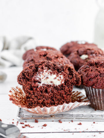 red velvet muffins filled with cream cheese icing on a cooling rack