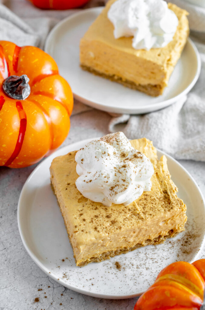 no bake pumpkin cheese bars on a plate topped with whipped cream