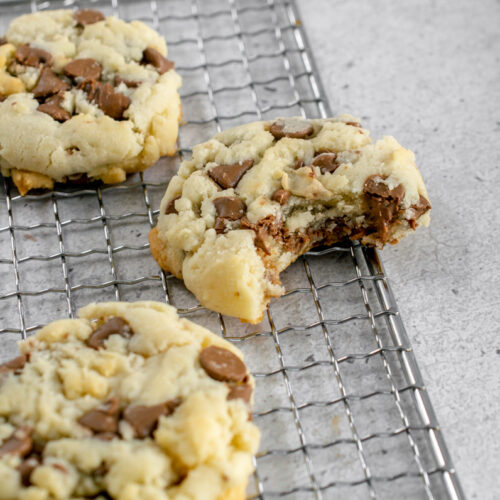 condensed milk chocolate chip cookies on a cooling rack with a bite taken out of one